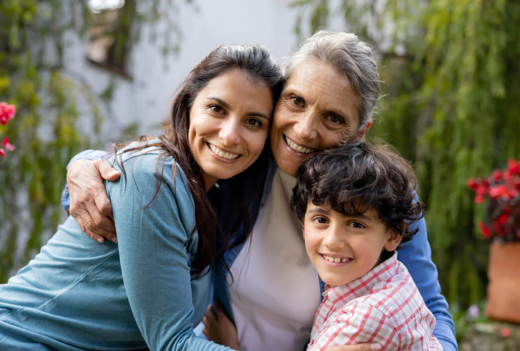 Generations United in Happiness Three generations of a family hugging and smiling outdoors.
